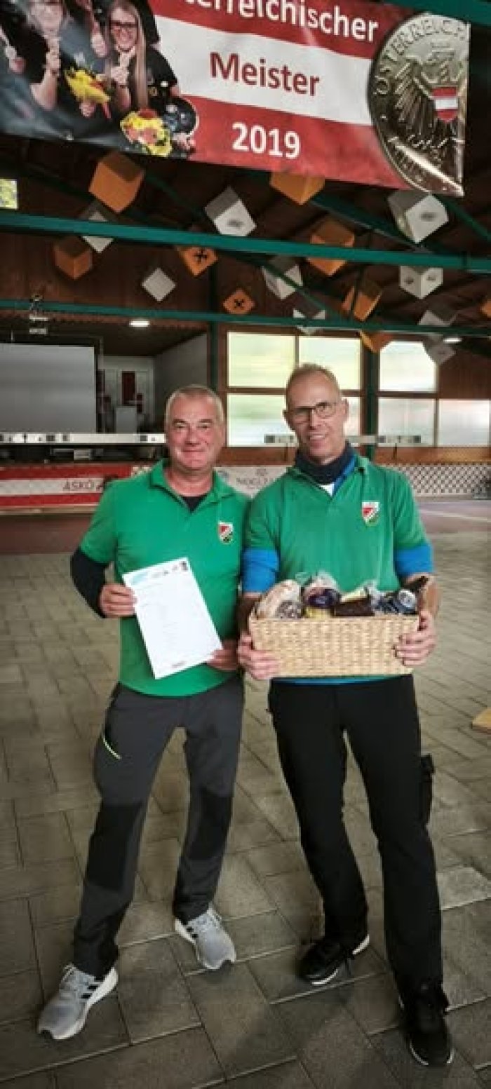 Meister 2019: Zwei Männer mit Urkunde und Präsentkorb in grünen Poloshirts.